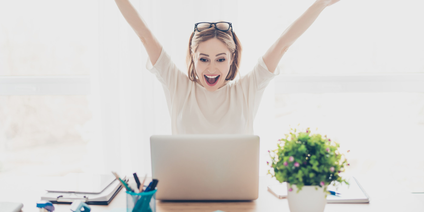 Woman on a laptop, delighted that her ticket has been completed.