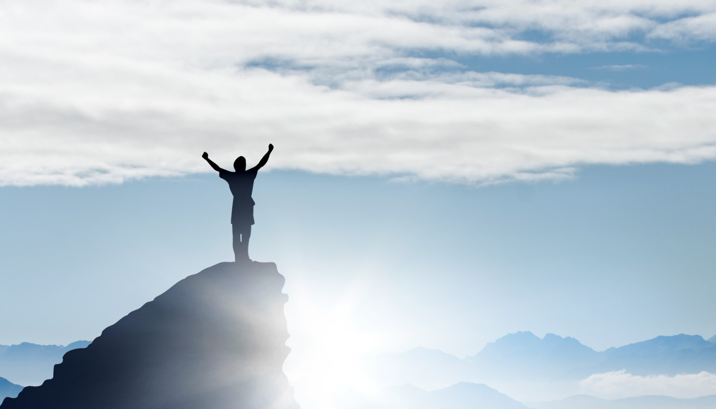 Man on mountaintop, celebrating him successful climb