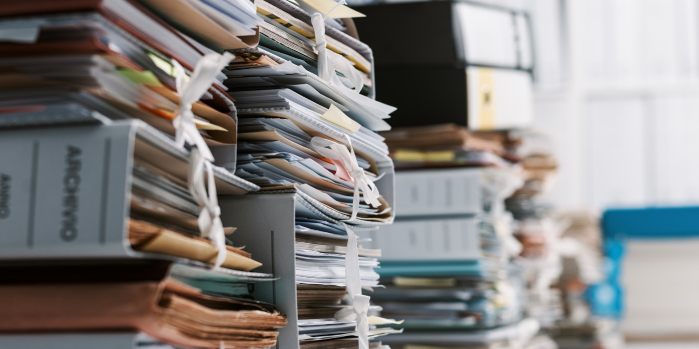 Piles of unsorted business documents on a desk in bundles.